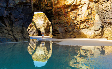 Woman walking on famous cathedral beach with natural rock arches- Galicia, Spain