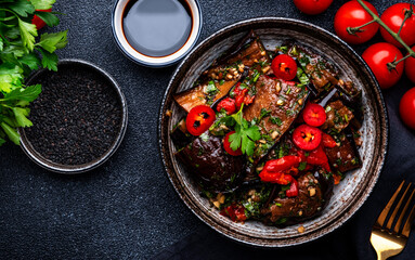 Grilled eggplant with red chili peppers, parsley, sesame seed, soy sauce and garlic in asian style,...