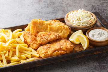 Tasty Fish Fry with coleslaw, French fries, tartar sauce and lemon closeup on the wooden board on the table. Horizontal