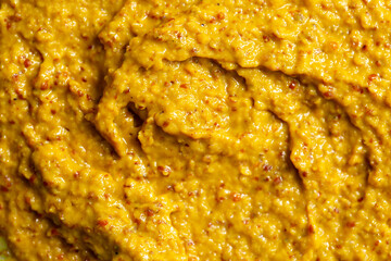 Mustard sauce with grains close-up. Hot spices as a background. Texture of Dijon mustard.