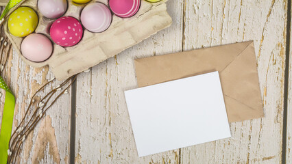 Mockup white greeting card, easter eggs and envelope on a wooden background