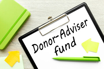Home office workplace with clipboard and pen with DONOR ADVIDER FUND text on white wooden background, business