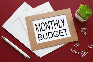monthly budget text on white paper in a frame on a red background
