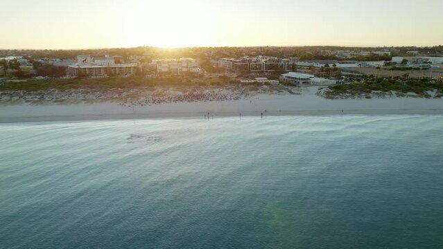 An aerial shot of Leighton beach with a group of swimmers and a large beach yoga session. Fremantle port can be seen in the back ground. 