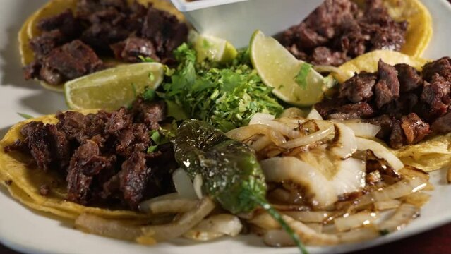 Traditional carne asada steak street tacos on corn tortillas with grilled onions cilantro and borracho beans, close up slider 4K