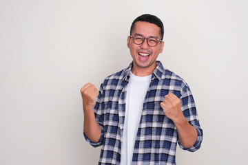 Adult Asian man clenching both hands showing excited expression