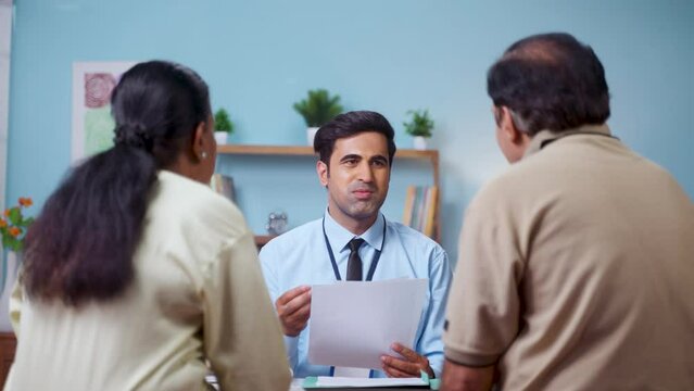 Shoulder shot, indian banker explaining about future investment plans or pension scheme offer to senio couple - concept of financial adviser, real-estate agent and consultant