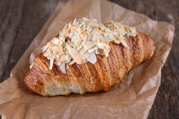 Almond croissant on craft paper on wooden background