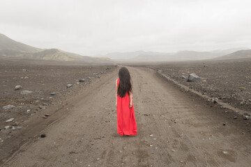 girl in red dress in misty landscape of Iceland on road to nowhere