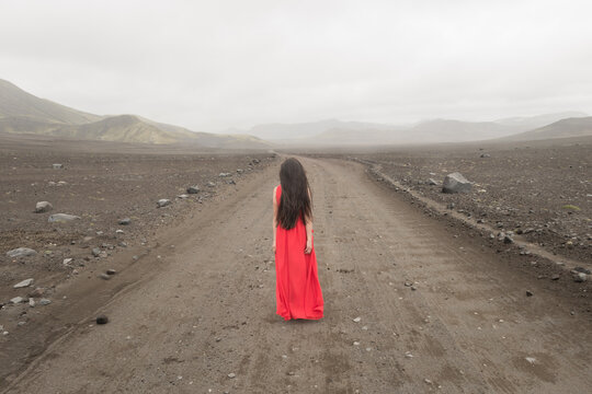girl in red dress in misty landscape of Iceland on road to nowhere