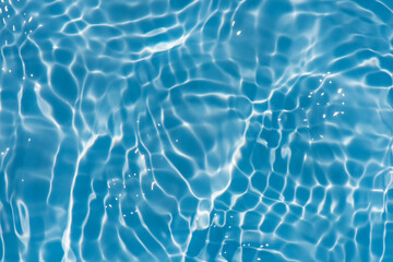 Fototapeta na wymiar Blue water with ripples on the surface. Defocus blurred transparent blue colored clear calm water surface texture with splashes and bubbles. Water waves with shining pattern texture background.