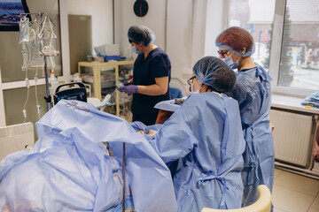 Team of surgeon in uniform perform varicose veins correction operation on a patient at surgery clinic