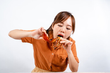 young asian woman enjoys eating seafood, crab with padang sauce (Indonesian : Kepiting Saus Padang)...