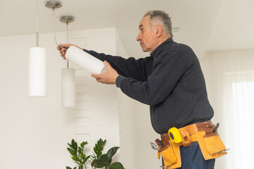 A male electrician changes the light bulbs in the ceiling light. men's household duties. care of...