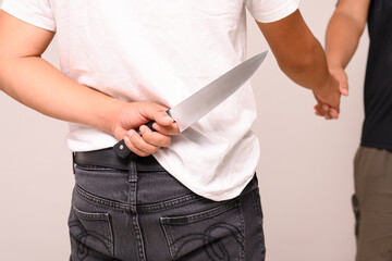 Two male shaking hand with one hand holding a knife on white background.Weak trust. Backstabbing...