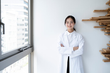 Smiling female doctor standing near window at hospital