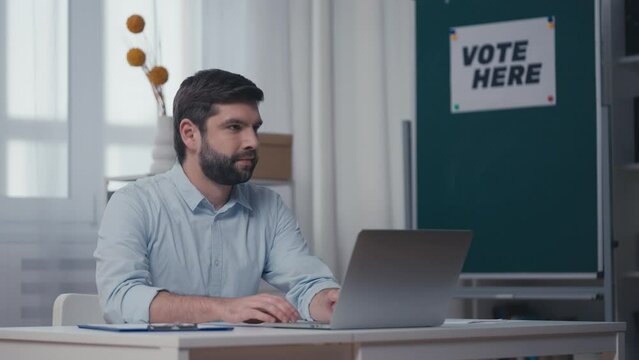 Young man working on computer at polling station, election day, slow motion
