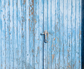 detail of an antique weathered wooden door painted blue