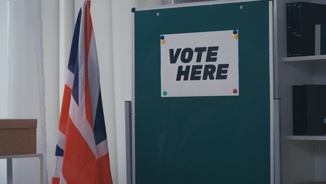 Vote here sign on wall, UK flag at polling station, democracy, freedom of choice