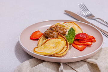 Cottage cheese pancakes, syrniki, curd fritters with strawberry, mint and powdered sugar on plate