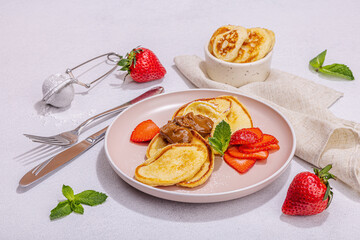 Cottage cheese pancakes, syrniki, curd fritters with strawberry, mint and powdered sugar on plate
