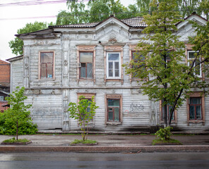 Old wooden two-storey houses with windows in the city of Tomsk, Russia. Dilapidated, residential housing in poor condition.
