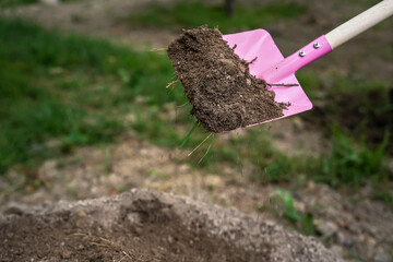 Working in garden - small pink shovel with some soil, closeup detail