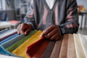 Close-up of African American designer choosing colour for interior while sitting at table