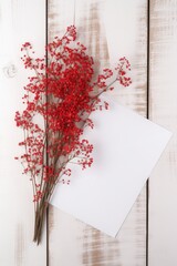 White Blank Paper Card Mockup and Red Berries Stem Bunch on Wooden Table Top. Generative AI.