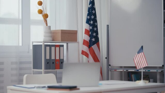 American school classroom with USA flag and laptop on desk, government agency