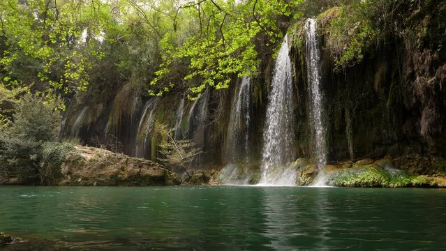 Beautiful nature of Turkey, waterfall and small lake, green trees branch hang over water. Idyllic picture of Kursunlu Waterfalls in spring time.