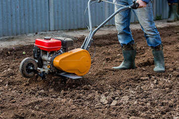 Banner. Man Farmer plows the land with a cultivator. Agricultural machinery: cultivator for tillage in the garden,motor cultivator.