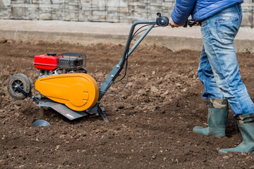 Banner. Man Farmer plows the land with a cultivator. Agricultural machinery: cultivator for tillage in the garden,motor cultivator.