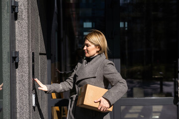 woman using intercom at building entrance.
