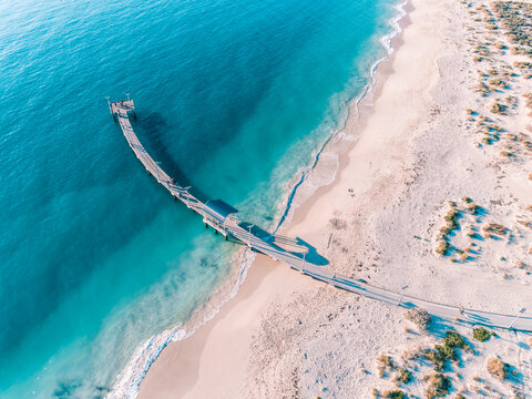 Aerial top down view of Jetty and beach with crystal turquoise water. Beach as a wallpaper. Beautiful natural summer vacation holidays background. Jurien Bay, Western Australia. Coastal seascapes