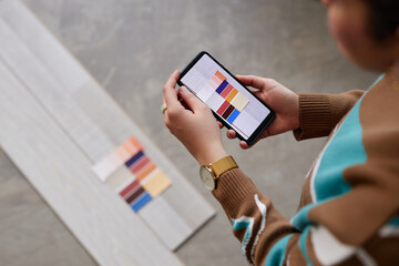Female designer using smartphone to make photo of color palette for choosing color for flooring
