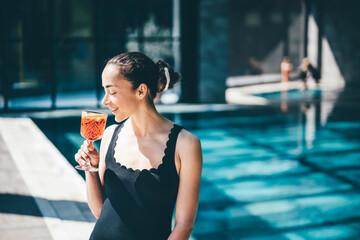 Young woman relaxation on poolside with cold and fresh Spritz cocktail