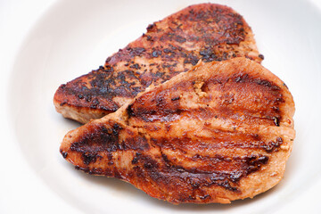 Grilled red tuna steak with pepper macro on a white plate.