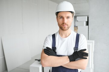 Portrait of positive, handsome young male builder in hard hat.