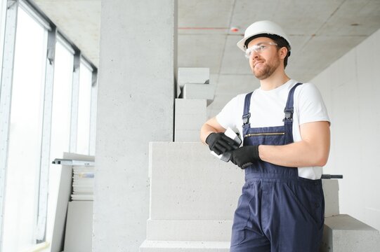 Portrait of positive, handsome young male builder in hard hat.