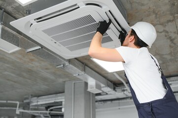 Happy Male Technician Repairing Air Conditioner