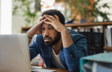 Young frustrated man sitting in front of computer in his office.