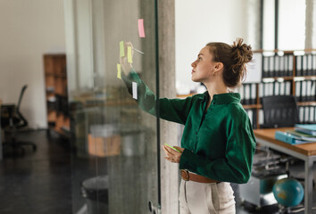 Young woman taking notes in her office.