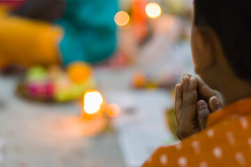 A child praying to hindu god or goddess with folded hands during pushpanjali offerings of puja...