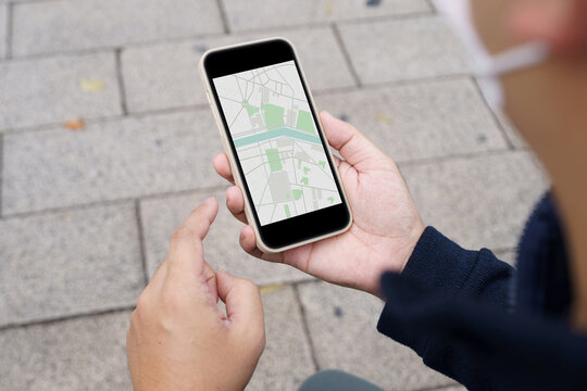 Woman with baggage&nbsp;in downtown city street searching location in map application online on smart phone using GPS&nbsp;navigating.