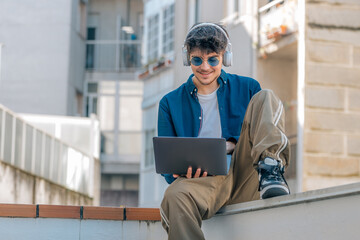 young man or student with laptop and headphones in the street