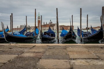 Gondolas in Venice in a cloudy day, with church in the background, Italy