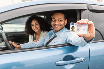 Arabic Couple Displaying Driving License Through Window Sitting Inside Car