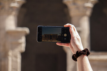 Mano di una ragazza che fotografa un tempio egizio con il suo cellulare