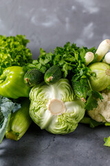 Variety of raw green vegetables on grey background. Copy space